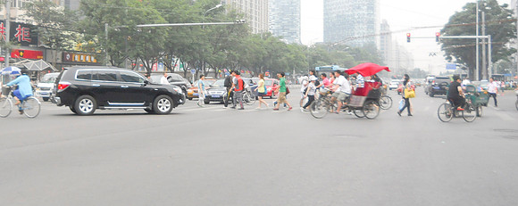 The black car will just turn right into these people and narrowly miss them.
