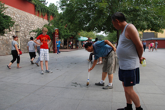 Doing calligraphy with water on the sidewalk.